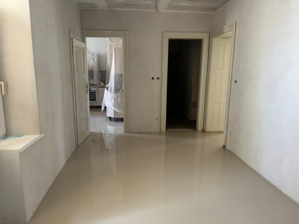 Rekonstruovaná chodba s nově vyrovnanou podlahou pomocí samonivelační stěrky, pohled směrem ke kuchyni.